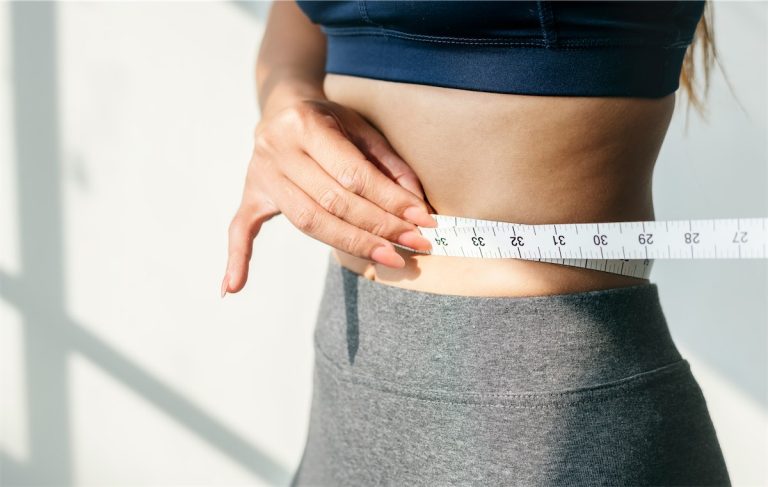 Medidor de cintura, mujer midiendo su cintura con cinta métrica, control de peso y salud.