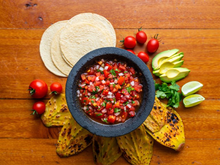 Refresco de agua fresca de tomate con jarra y variedad de ingredientes frescos sobre mesa de madera.